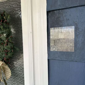 photo of homeowner plaque on exterior siding of a blue home